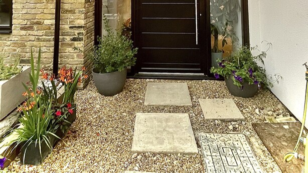 A modern building with a black door, stone walls, and potted plants. - Grand open plan modern home with heaps of light, and close to London (Kingston upon Thames)
