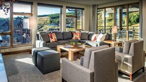 A spacious living room with a large sectional sofa, a coffee table, and a view of a scenic landscape through large windows. - Ski In - Ski Out, One-Bedroom Breckenridge Residence Peak 8, Corner unit (Breckenridge)