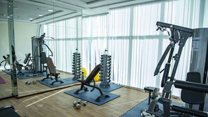 Ett gym med olika typer av träningsutrustning, inklusive styrketräningsmaskiner och lösa vikter, placerade på mattor.