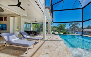 A modern indoor pool area with lounge chairs, a dining area, and a view of the ocean. - Intervillas Florida - The Diamond (Cape Coral)