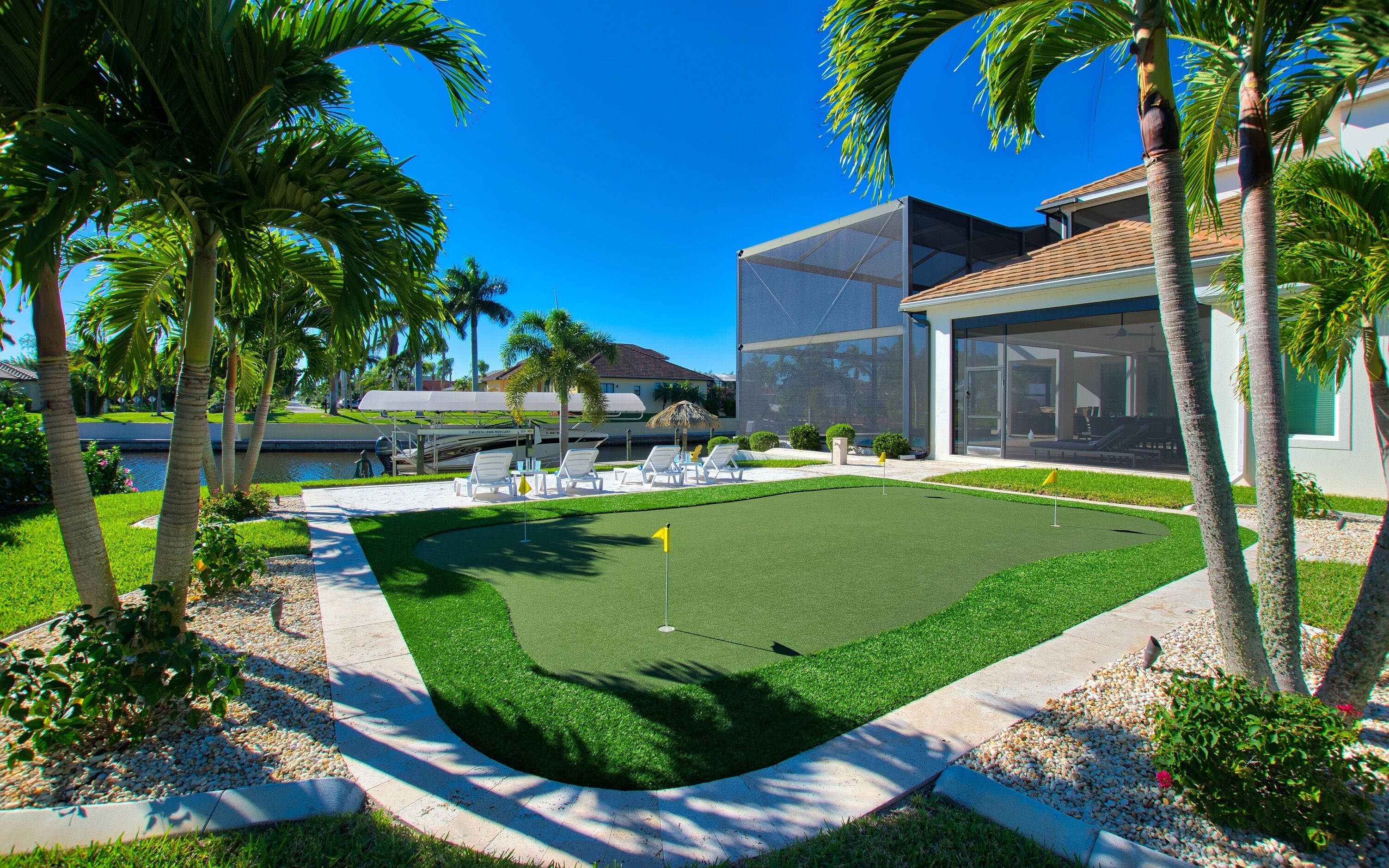 A modern building with a glass facade, a well-maintained lawn, and a pool area with lounge chairs.