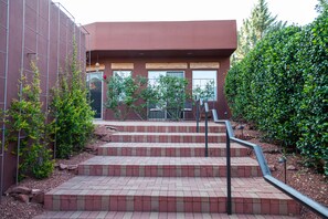 Ein Gebäude mit roter Backsteinfassade, einer Treppe, die nach draußen führt, und einem Zaun links.