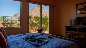 Een slaapkamer met een groot bed, een televisie en uitzicht op een berg door een raam.