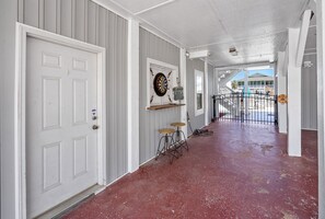 Enter a welcoming corridor with a red floor, leading to a gated entrance and a cozy area with a dartboard and two stools.