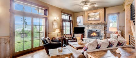 Una sala de estar acogedora con chimenea, ventanas amplias y un televisor.