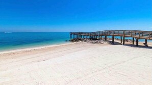Una playa con un muelle de madera que se adentra en el mar.