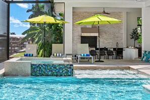 Ein Poolbereich mit Whirlpool, Liegestühlen und Sonnenschirmen.