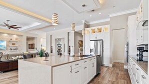 Una cocina moderna con armarios blancos, una isla central e iluminación colgante.
