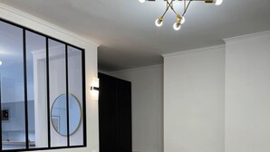 Ett modernt sovrum med en stor säng, en rund spegel, en svart garderob och en taklampa.