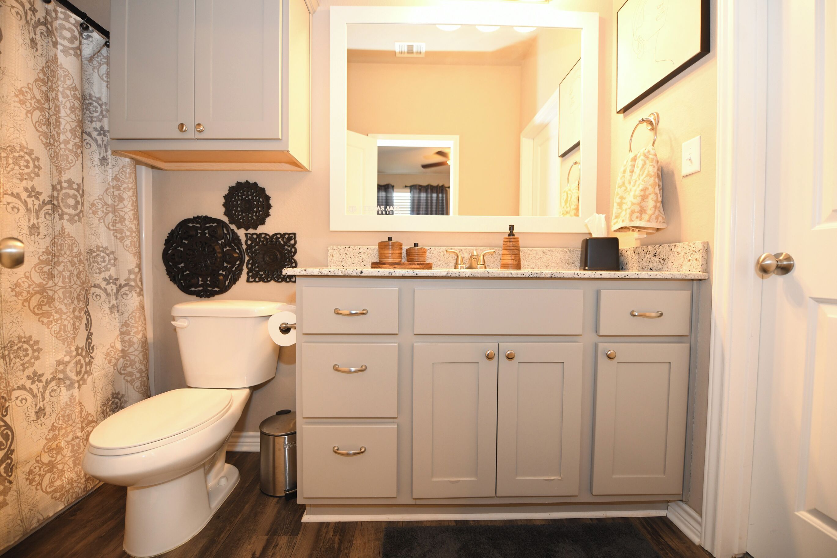 A bathroom with a toilet, vanity, and cabinets.