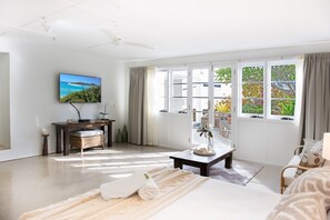 A spacious room with a bed, a desk, a television, and a view of the outdoors through large windows. - Airlie Beach Seaviews (Airlie Beach)