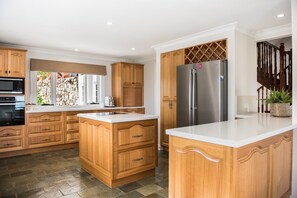 Une cuisine moderne avec des meubles en bois, un réfrigérateur en acier inoxydable et un grand îlot central.