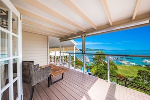 A balcony with a view of a marina and boats, a wicker chair, and a wooden table. - Airlie Beach Seaviews (Airlie Beach)