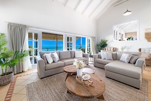 A spacious living area with a large window overlooking a scenic view, furnished with sofas and a coffee table. - Airlie Beach Seaviews (Airlie Beach)