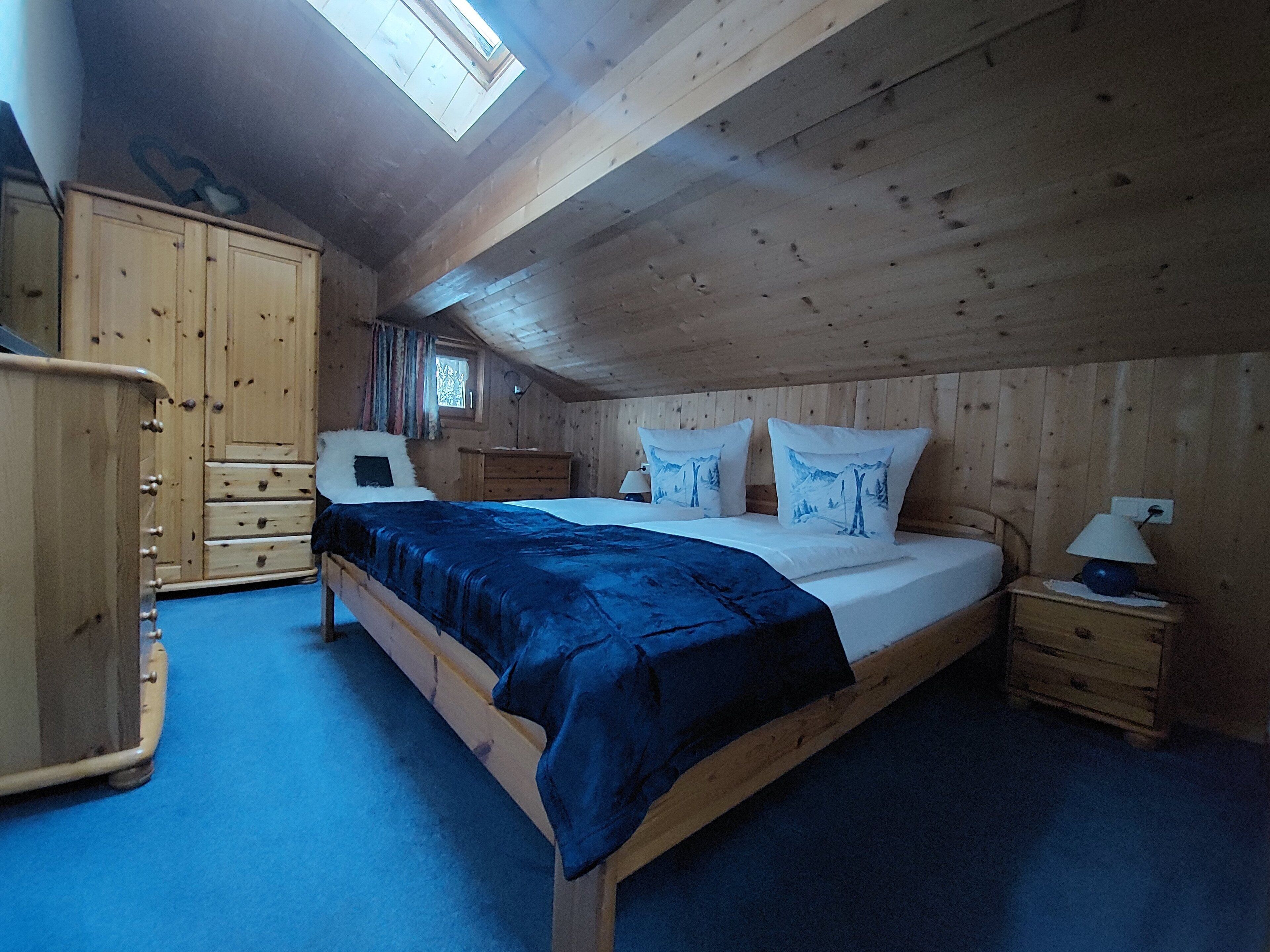 Une pièce en bois avec un lit, une armoire, une table de chevet et une fenêtre.