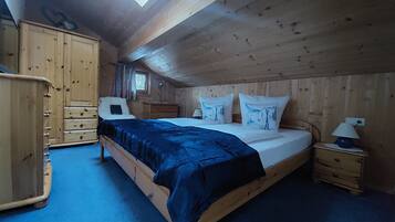 Une pièce en bois avec un lit, une armoire, une table de chevet et une fenêtre.