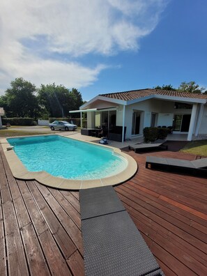 Relax by the pool surrounded by a lush lawn and trees.