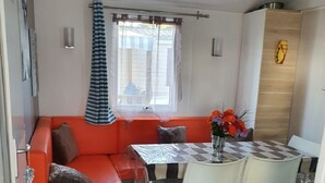 Un ambiente compatto con un divano, un tavolo da pranzo con sedie e una finestra con tende.