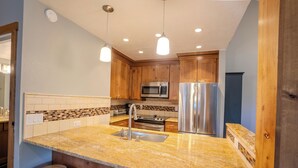 A kitchen with granite countertops, stainless steel appliances, wooden cabinets, and pendant lighting. - 300 off for Christmas 12/23-26 Ski in/Walk Out. Private Hottub Sleeps 8 2Br+Loft (Park City)