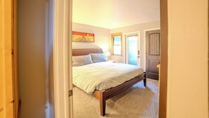 A bedroom with a bed, a nightstand, a wall-mounted painting, and a door. - 300 off for Christmas 12/23-26 Ski in/Walk Out. Private Hottub Sleeps 8 2Br+Loft (Park City)