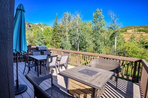 Une terrasse en bois aménagée avec du mobilier d’extérieur, notamment une table et des chaises, ainsi qu’un barbecue.