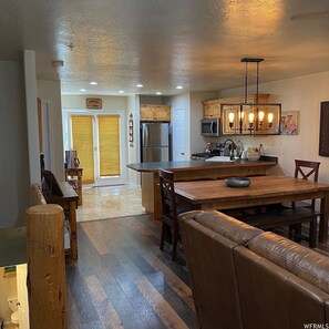 A spacious kitchen with wooden cabinets, a central island, and a dining area with a leather couch.