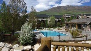 Ett semesterområde med en swimmingpool, gäststugor och en bergskedja som bakgrund.