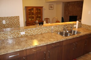 Una cocina con encimeras de granito, fregaderos de acero inoxidable y armarios de madera.