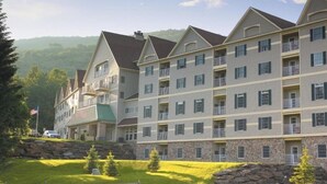 Un hotel de varios pisos con fachada de piedra, balcones y vistas del paisaje circundante.