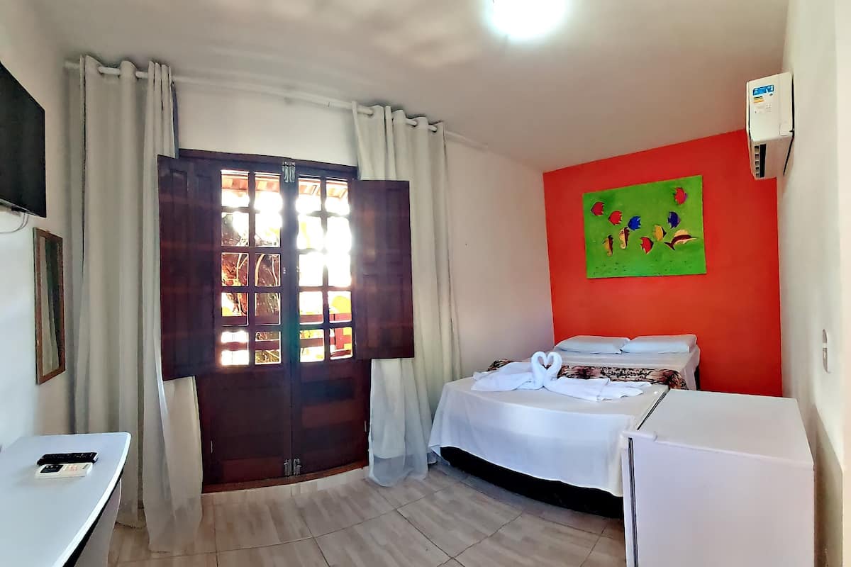 Una habitación con cama, escritorio, ventana con cortinas, un cuadro en la pared y una lámpara en el techo.