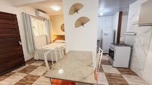 A compact kitchen with a dining table, a refrigerator, and a stove. - Pousada Porto  Amazônia (Ipojuca)