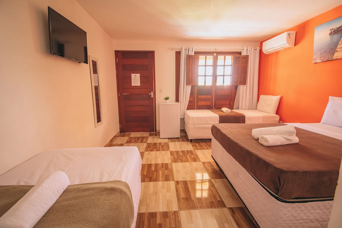 Habitación de hotel con dos camas, televisión, aire acondicionado y ventana con cortinas.