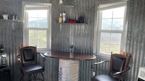 Una cocina rústica con una barra circular, dos sillas y vistas a las montañas a través de amplios ventanales.