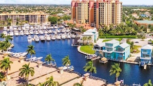 A marina with boats, a hotel with colorful buildings, and a river. - Seabreeze Oasis - 4 Br 3 Ba Lakefront Home w/ Heated Pool, Kayaks + more (Cape Coral)