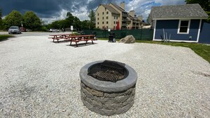 A gravel parking area with picnic tables and a stone fire pit. - Charming Studio Condo at Mt Green: Renovated, Steps to Mtn 3C13A (Killington)