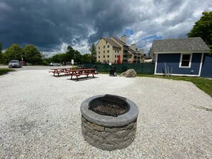 Un aparcamiento de grava con mesas de picnic y un hogar de fuego de piedra.