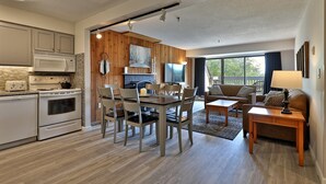 A modern kitchen with a microwave, stove, and dining area with chairs and a table.