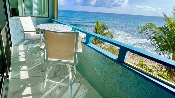 Un balcone con vista sull'oceano, un tavolo e due sedie.