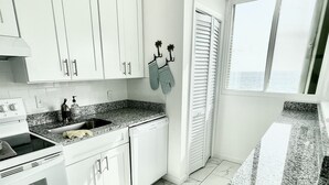Una cucina moderna con mobili bianchi, un piano di lavoro in granito e un cestino nero.