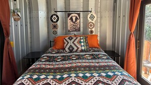 Une chambre à coucher avec une couvre-lit à motifs, une pancarte « Bienvenue » et des décorations murales.