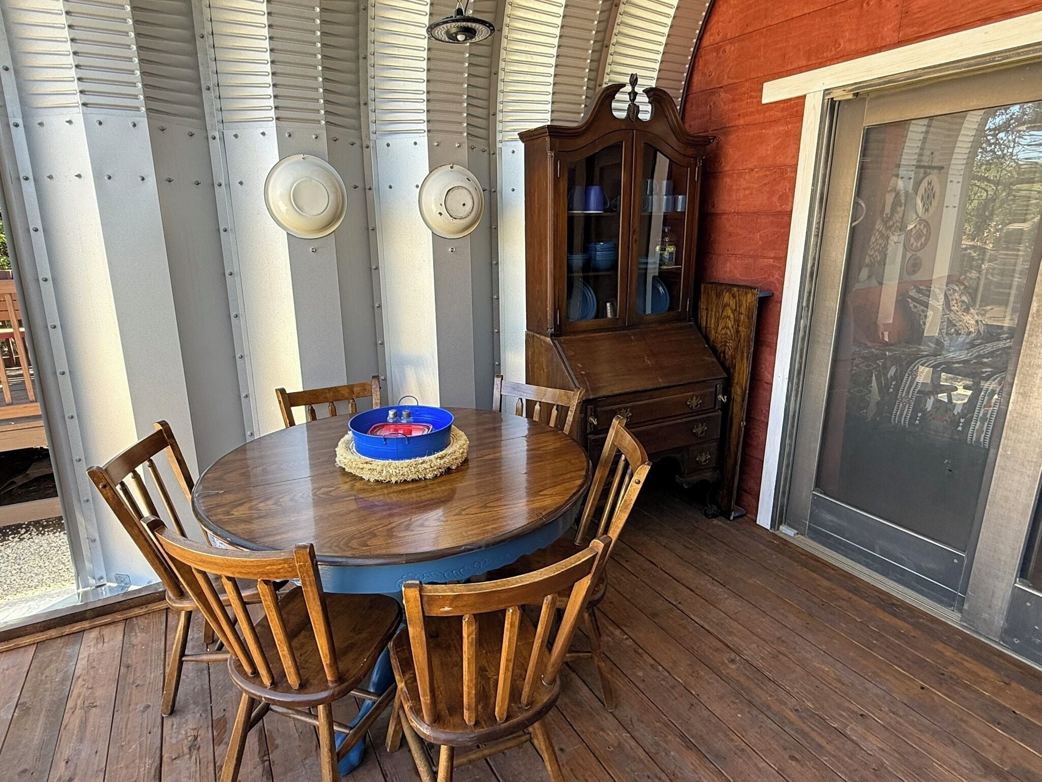 A wooden dining table with six chairs, a blue bowl, and a cabinet with glass doors.