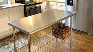 Una cocina moderna con gabinetes blancos, electrodomésticos de acero inoxidable y una isla central.