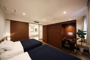 Una habitación de hotel con dos camas, un escritorio, una silla y una planta en maceta.
