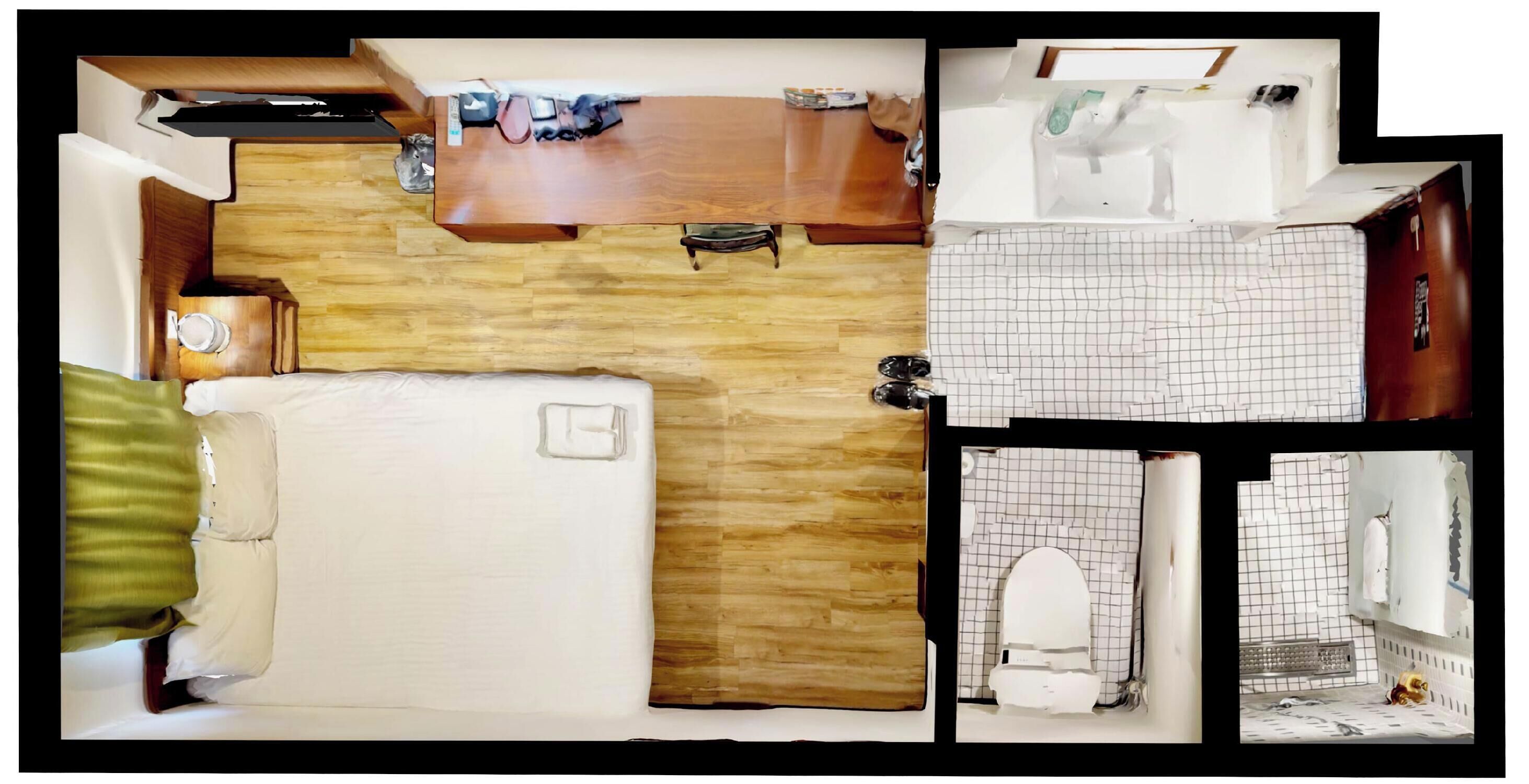 Een kamer met een bed, een houten bureau, een stoel, een klein tafeltje en een badkamer met toilet en wastafel.