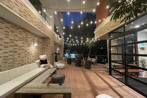 An outdoor seating area with brick walls, string lights, and potted plants.