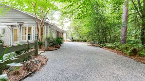 Une allée de gravier mène à une rangée de maisons de plain-pied, avec une forêt en arrière-plan.