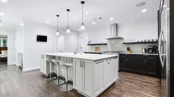 A modern kitchen with white cabinetry, a central island, bar stools, and stainless steel appliances.