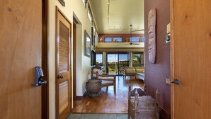 A hallway with wooden doors, a wicker chair, a wooden bench, and a ceiling fan.