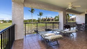A covered outdoor area with a pool table, lounge chairs, and a view of a golf course.