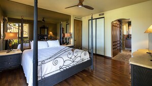 A four-poster bed with a mirror above, a ceiling fan, and a wooden floor.